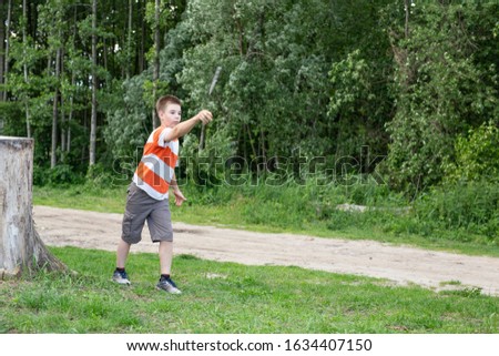 Boy throwing a knife, exercing in forest.