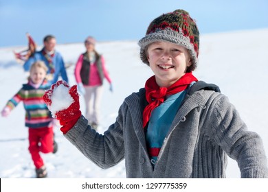 Boy Throwing Snowball With Family Smiling At Camera In Snowy Landscape