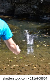 boy throwing a stone to the river doing splash