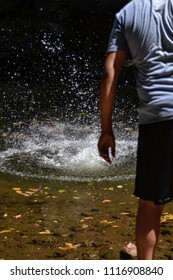boy throwing a stone to the river doing splash