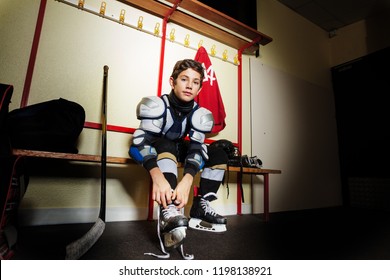 Boy ties hockey skates laces in dressing room - Powered by Shutterstock