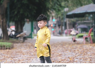 The boy in traditional Vietnamese costume plays along the road with beautiful trees at sunset in Hanoi, Vietnam. date 04/03/2018