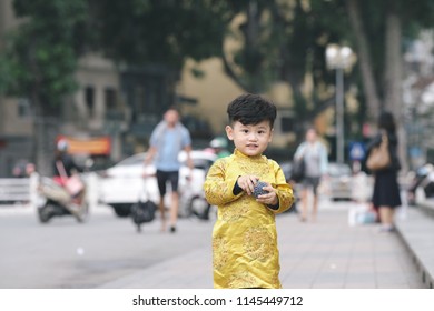 The boy in traditional Vietnamese costume plays along the road with beautiful trees at sunset in Hanoi, Vietnam. date 04/03/2018