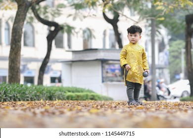 The boy in traditional Vietnamese costume plays along the road with beautiful trees at sunset in Hanoi, Vietnam. date 04/03/2018