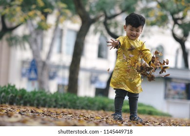 The boy in traditional Vietnamese costume plays along the road with beautiful trees at sunset in Hanoi, Vietnam. date 04/03/2018