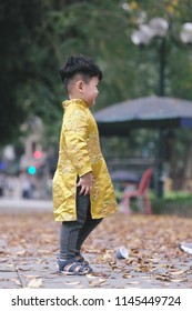 The boy in traditional Vietnamese costume plays along the road with beautiful trees at sunset in Hanoi, Vietnam. date 04/03/2018