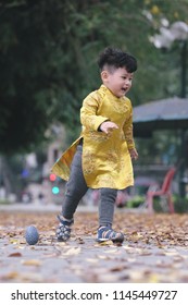 The boy in traditional Vietnamese costume plays along the road with beautiful trees at sunset in Hanoi, Vietnam. date 04/03/2018