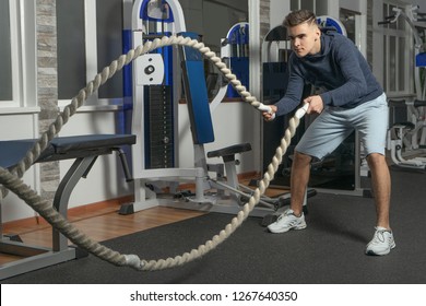 A Boy Is Training With Battle Rope In Gym