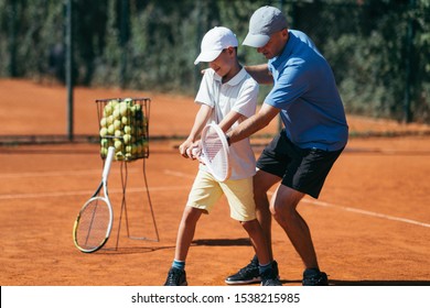 Boy Training with Tennis Instructor on a Clay Court