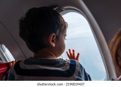 Boy Traveling By Plane On Vacation Looking Out The Window, Looking At The Sky For The First Time Flying