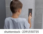 Boy tries to push the elevator button up and down. Child stretches out his hand and finger to press the button