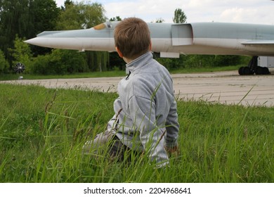 The Boy Turned And Looks At The Cruise Missiles Near The Strategic Bombers On The Runway Of The Military Airfield
