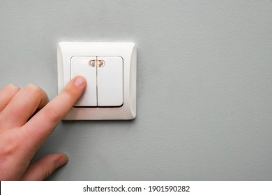 the boy turns off the light on the switch on the wall in the room. Electricity consumption.