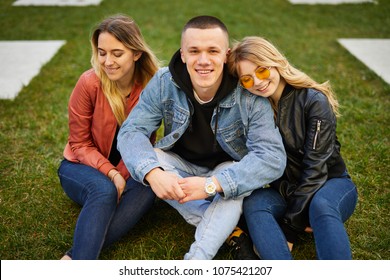 Boy With Two Girls On The Green Grass Talking And Smile To Camera