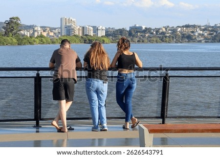 A boy and two girls on the pier observing a river.