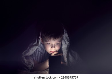 boy under the covers with a phone at night. gadget addicted children. teenager man use mobile phone at night in the room under the covers - Powered by Shutterstock