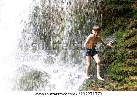 Boy under waterfall Shum on Rufabgo stream, Adygea