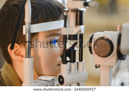 Boy undergoing an eye examination using a slit lamp biomicroscope by ophthalmologist in a modern clinic