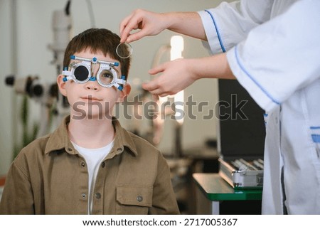 Boy undergoing vision testing with ophthalmologist using trial frame in medical clinic, checking visual acuity and eye health