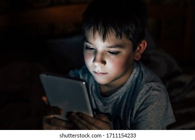 Boy uses a computer tablet at night - Powered by Shutterstock