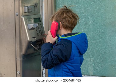 Boy uses a pay phone with a pink handset