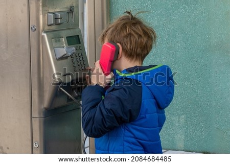 Boy uses a pay phone with a pink handset