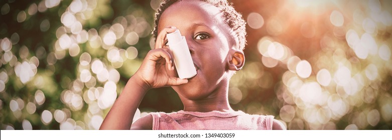 Boy using a asthma inhalator in a park - Powered by Shutterstock