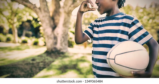 Boy using asthma inhaler in the park on a sunny day - Powered by Shutterstock