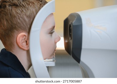 Boy using autorefractor during vision test in ophthalmology clinic, checking eyesight and diagnosing potential vision problems
