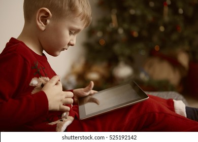 Boy Using His Tablet Under The Christmas Tree