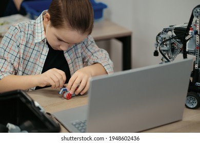 Boy using a laptop to program assembled robot from plastic bricks. STEM Education for kids.