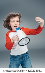 Boy using loudspeaker isolated on gray 