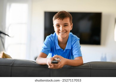 A boy using remote control on sofa at home
