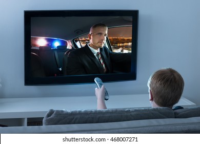Chlapec pomocí dálkového ovládání při sledování filmu v televizi doma