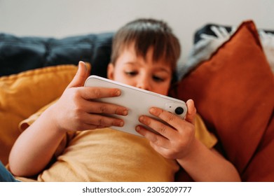 Boy using smart phone lying on the sofa.. - Powered by Shutterstock