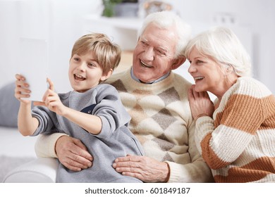 Boy using tablet device, taking selfie with grandparents - Powered by Shutterstock