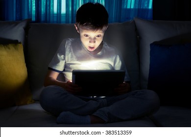 Boy Using Tablet Pc At Night. Boy With Tablet Computer In A Dark Room.