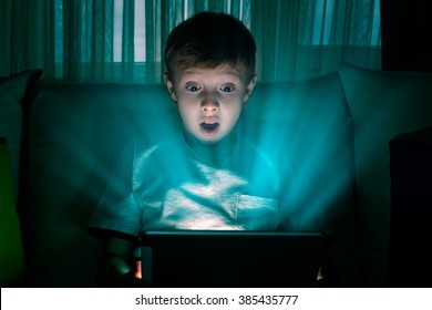 Boy Using Tablet Pc At Night. Boy With Tablet Computer In A Dark Room.