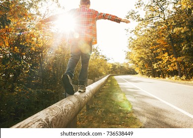 boy walking along the road fence. child keeps balance on the log. copy space for your text - Powered by Shutterstock