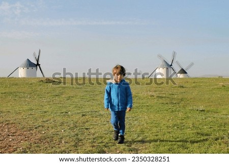Boy walking in a field with windmills in Spain
