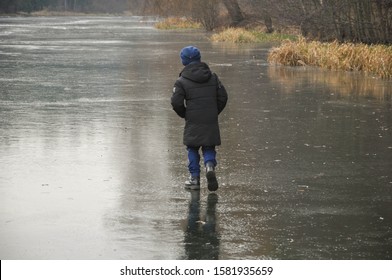 A Boy Walks On The Thin Ice Of A Pond.