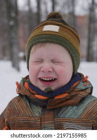 A Boy In A Warm Winter Jacket Squints His Eyes And Smiles.  The Boy Is Crying And Screaming.