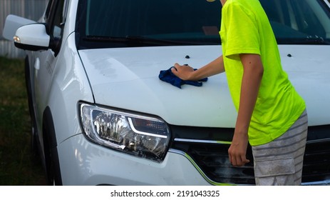 A Boy Washes A White Car With A Rag In The Summer At The Dacha Himself.