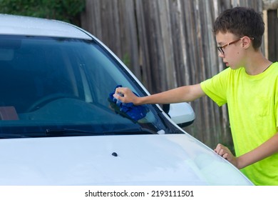 A Boy Washes A White Car With A Rag In The Summer At The Dacha Himself.