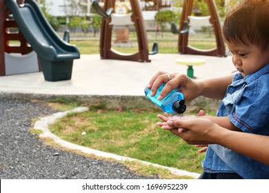 A Boy Washing His Hands With Alcohol Gel To Kill Germs And Have A Playground Background In The Park