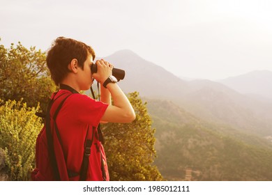 Boy Watches The Birds Through The Binoculars Against The Background Of The Mountains. Ornithology. Birdwatching