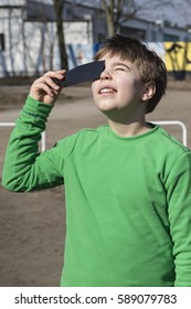 A boy watching a solar eclipse through a dark glass. Poland.
