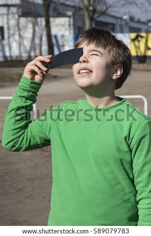 A boy watching a solar eclipse through a dark glass. Poland.