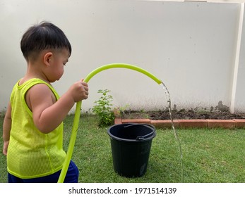 The Boy Was Watering The Plants In The Garden Next Door In The Hot Weather.