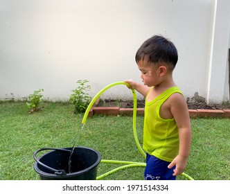 The Boy Was Watering The Plants In The Garden Next Door In The Hot Weather.